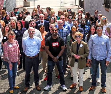 WCG team members standing in a parking lot with groovy sunglasses